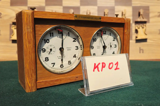 Front view of a working vintage wooden chess clock from the 1960s. Features original analog dials by H. Koopman Dordrecht and a plaque reading C. Kommandeur-Klok. Model KP01.