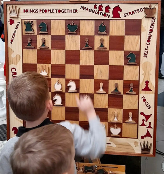 Children playing on a handmade wooden vertical chessboard by ChessboArt at Silesia City Center