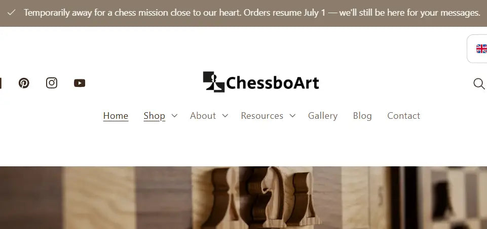 ALT propozycja: ChessboArt homepage banner announcing a temporary break for a chess mission with orders resuming July 1, over a wooden chessboard background