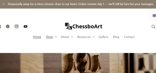 ALT propozycja: ChessboArt homepage banner announcing a temporary break for a chess mission with orders resuming July 1, over a wooden chessboard background