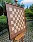 Premium wall-mounted chess board by ChessboArt in American Walnut and Ash. Elegantly displayed outdoors.