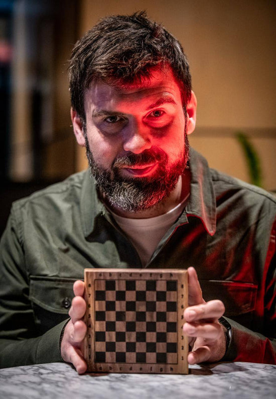 Artistic portrait of FM Michał Fudalej holding a custom wooden ChessboArt board, taken by famous chess photographer David Llada during the European Championship.