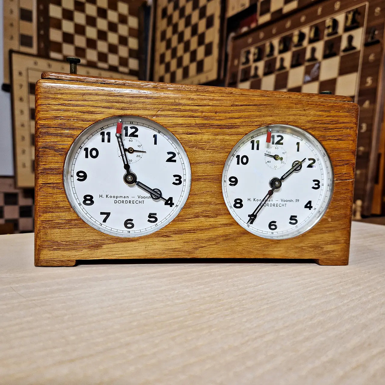 Close-up of vintage Koopman mechanical chess clock dial face showing original patina and hands.