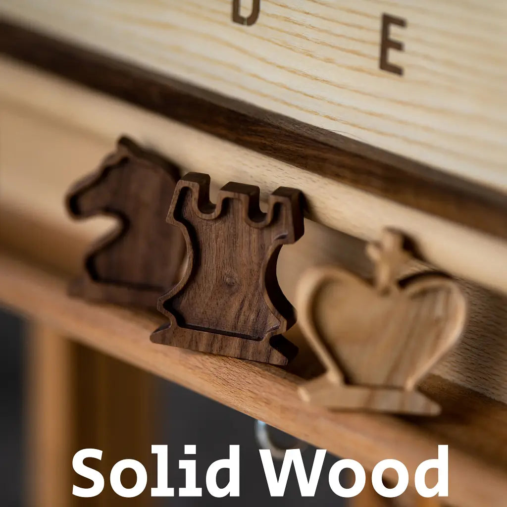 Close-up of Solid Wood magnetic chess pieces (Knight, Rook, King) resting on the rail of the wall board. American Walnut and Ash wood.