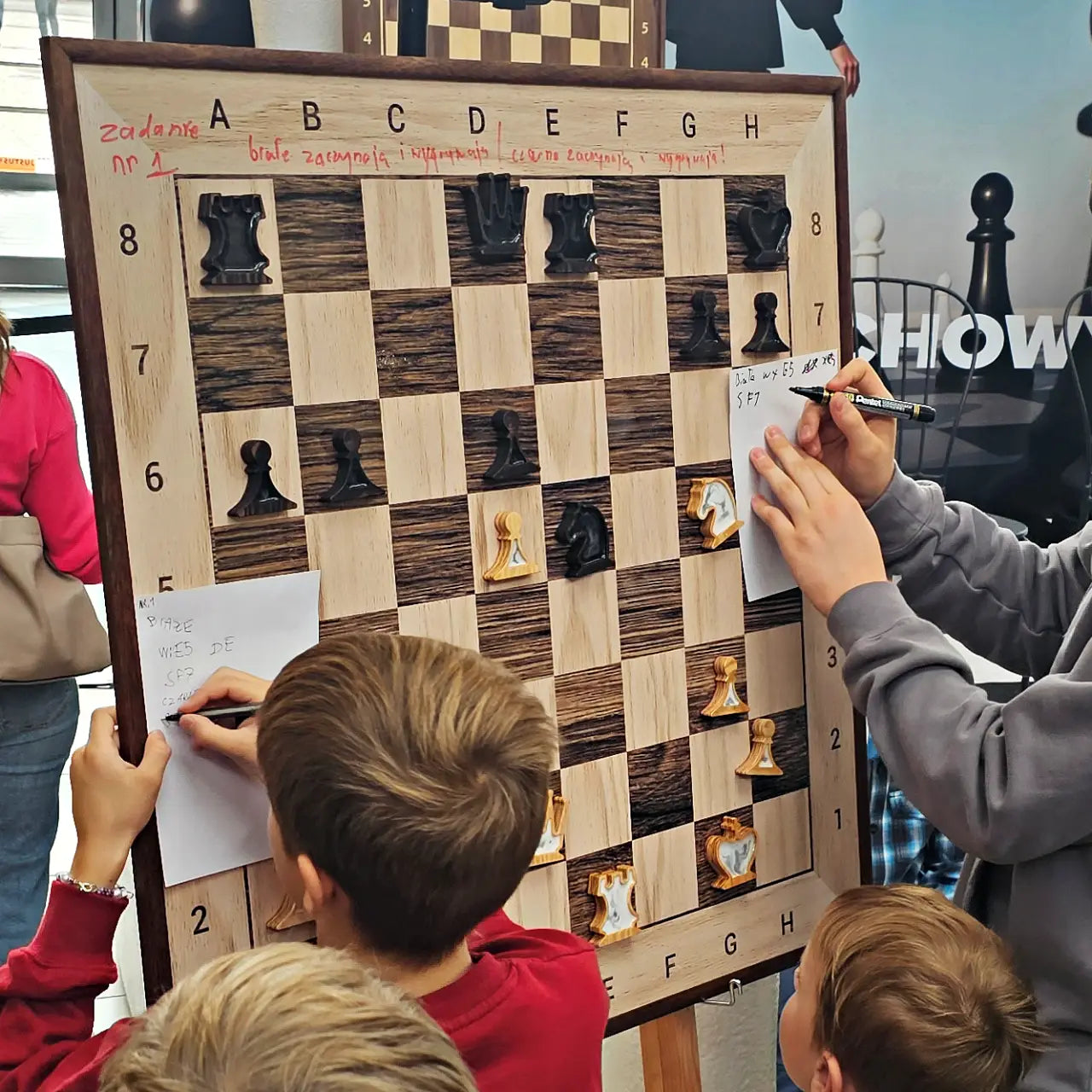 Children solving a chess puzzle on the ChessClub wall chess board at a tournament