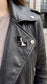 ChessboArt pin fastened to a black biker jacket lapel, urban street style shot