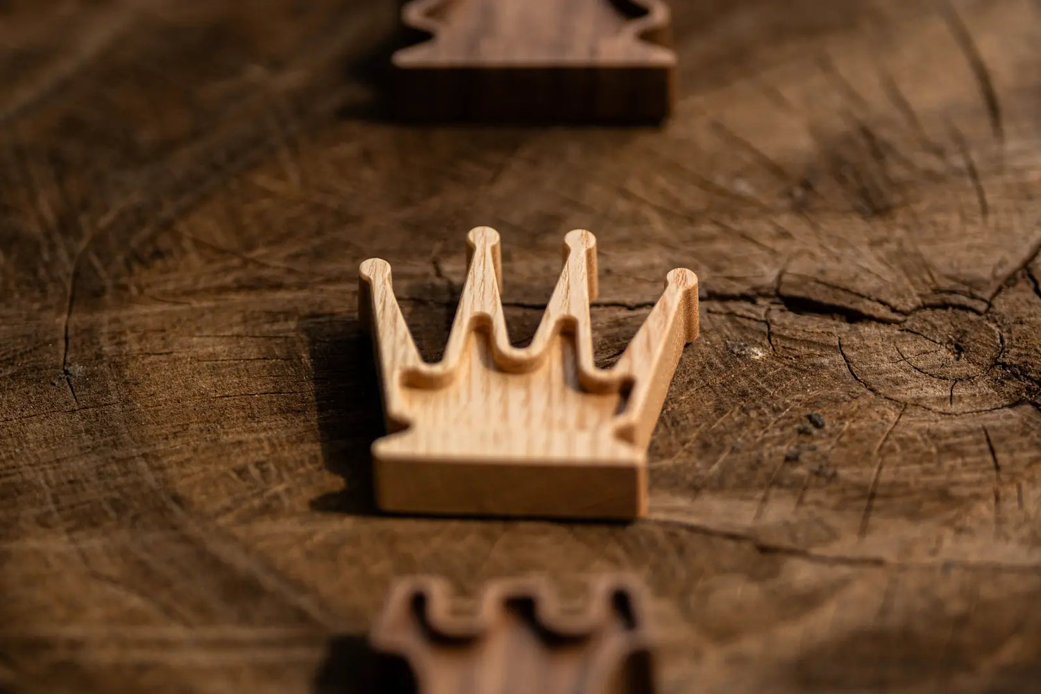 ChessboArt wooden chess queen standing on a natural tree trunk stump alongside two rooks.