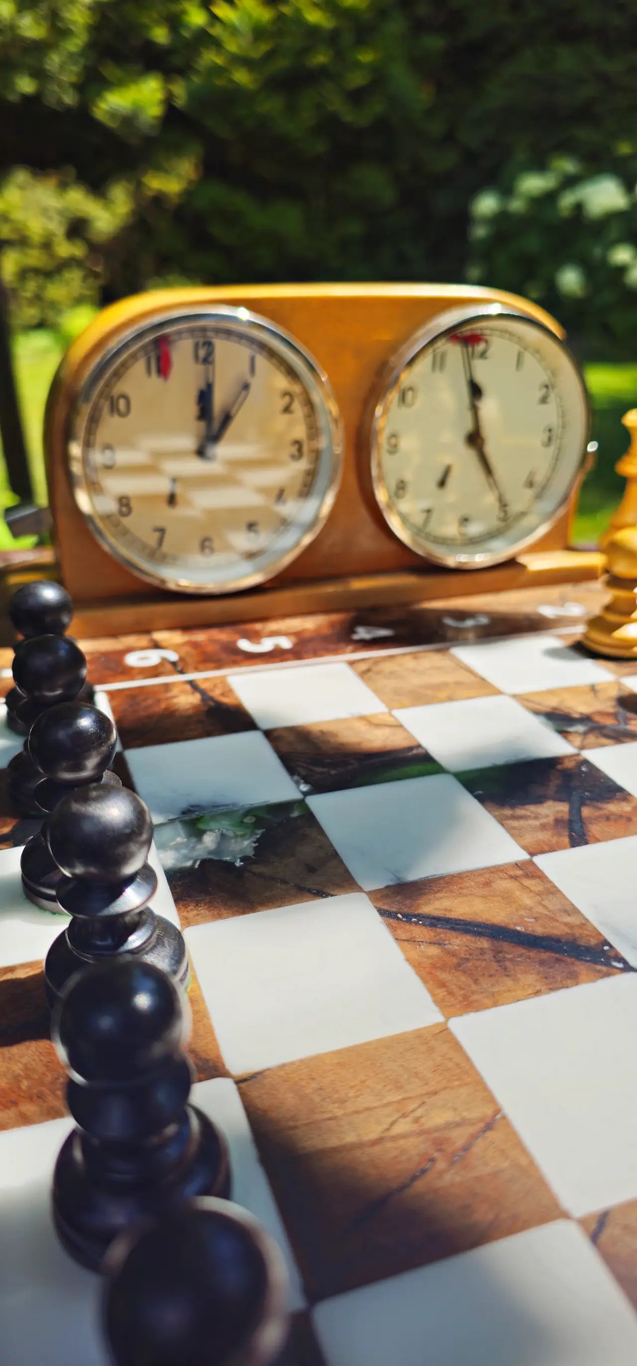 Close-up of the glossy epoxy resin playing surface and chess clock on the ChessboArt walnut table.