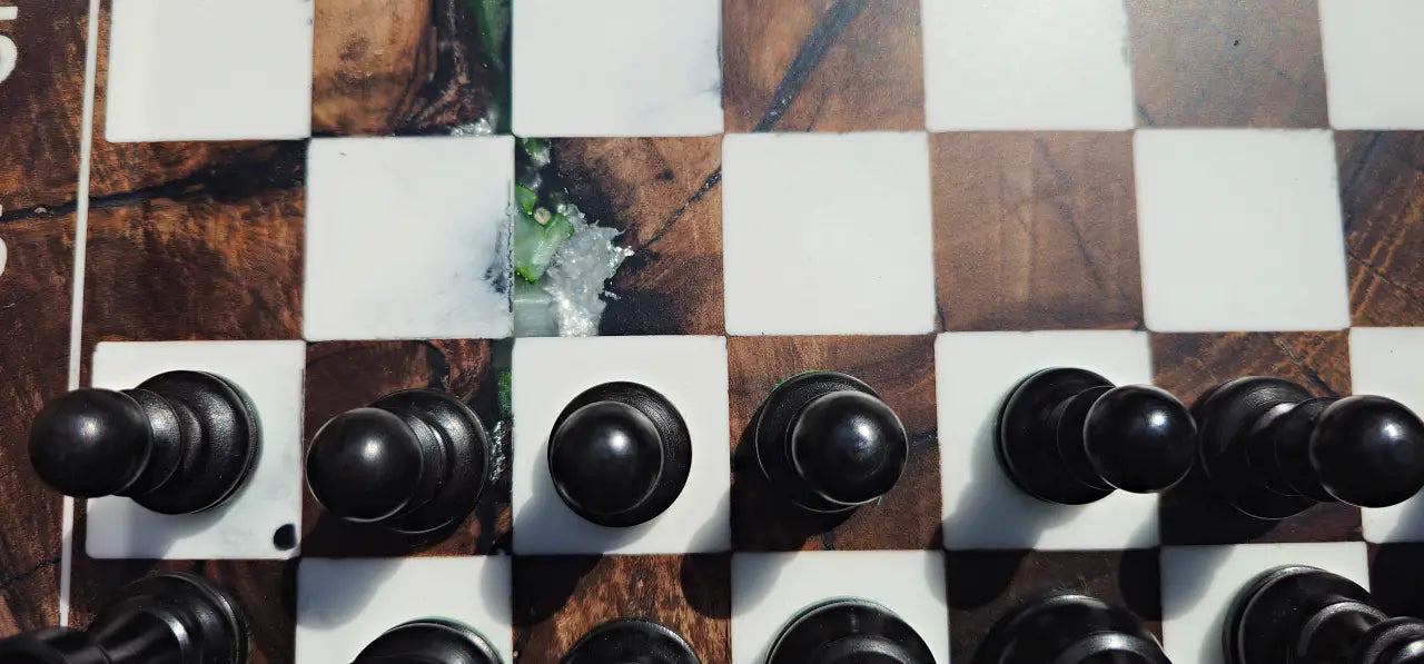 Top-down close-up of the ChessboArt walnut chessboard, highlighting the deep epoxy resin details, wood grain, and black pawns