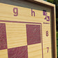 Macro shot of the top right corner of the pink ash wood chessboard, featuring the purple ChessboArt logo, coordinate numbers 7 and 8, and the edge of the natural ash wood frame.