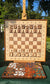 Wall chess set with unfilled wooden pieces and a tray of interchangeable magnetic epoxy resin color inlays