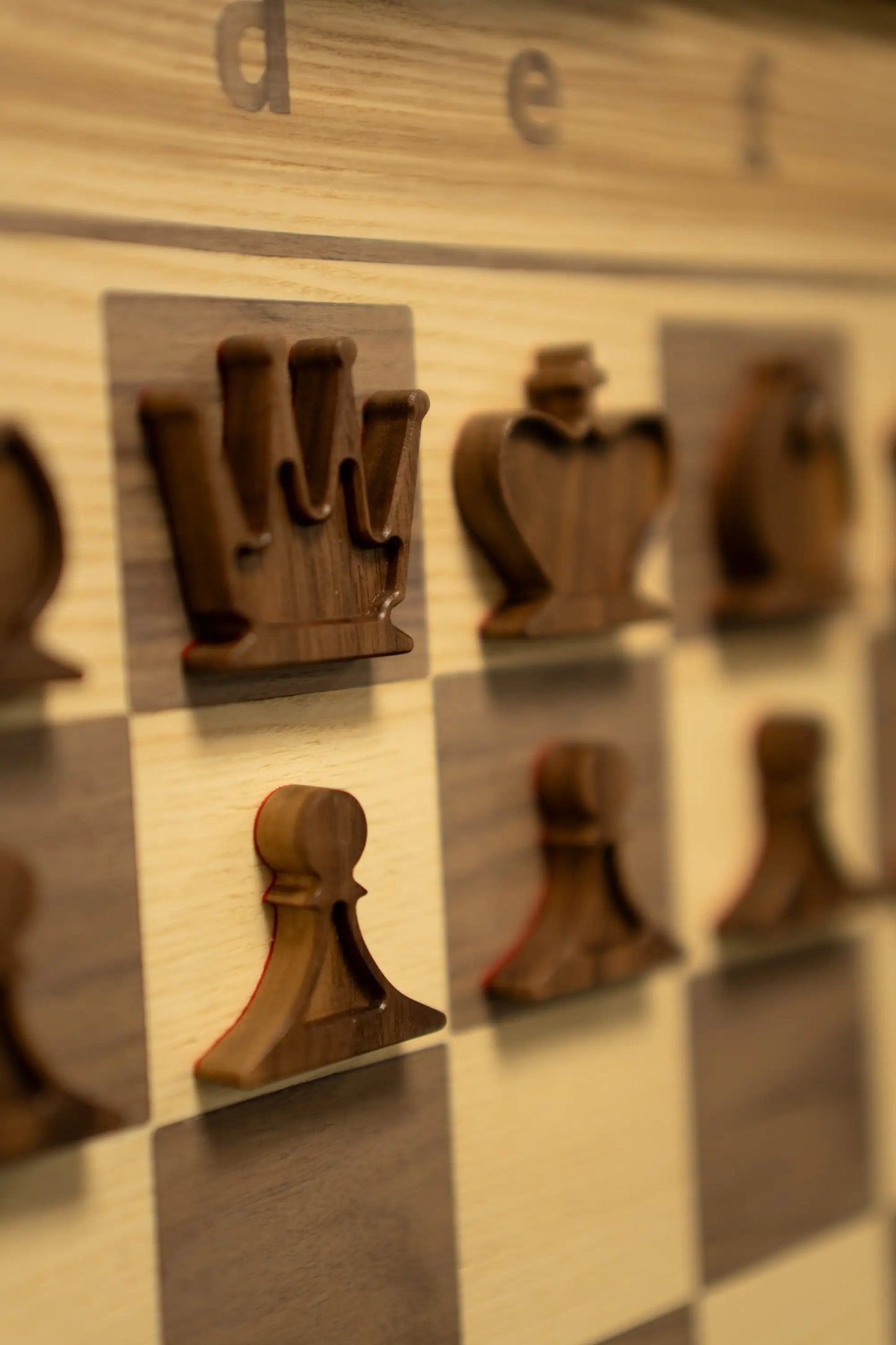 A close-up shot of uniquely designed flat wooden chess pieces on a ChessboArt demonstration board during the EICC 2026 in Katowice