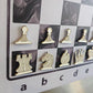 Cream and gold enamel chess pieces shaped like pin badges on the Epoxy Ivory magnetic board