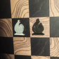 Black and cream enamel bishop chess pieces shaped like pin badges on the Ivory Grain magnetic board