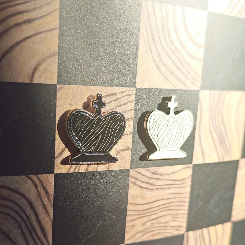 Black and cream enamel king chess pieces shaped like pin badges on the Ivory Grain magnetic board