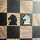 Black and cream enamel knight chess pieces shaped like pin badges on the Ivory Grain magnetic board