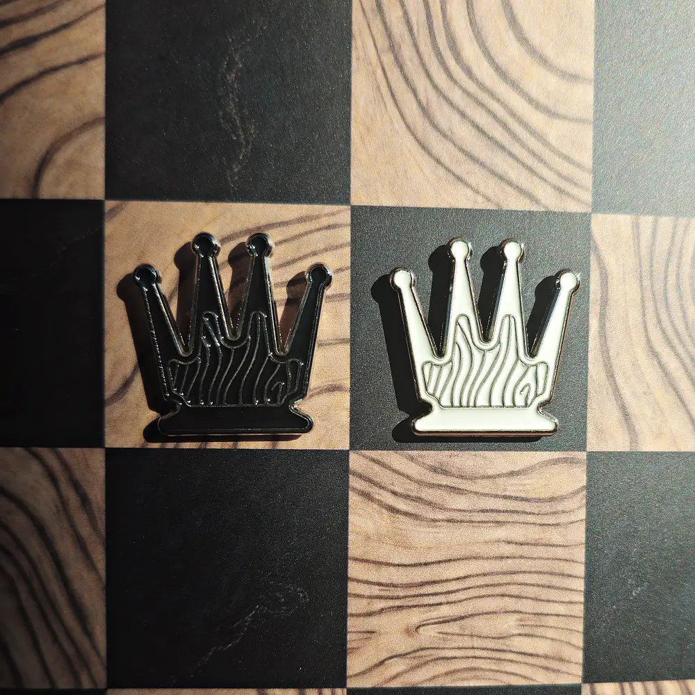 Black and cream enamel queen chess pieces shaped like pin badges on the Ivory Grain magnetic board