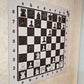 Vertical magnetic chess set with Ivory Grain board mounted on a wall, angled view of a mid-game position