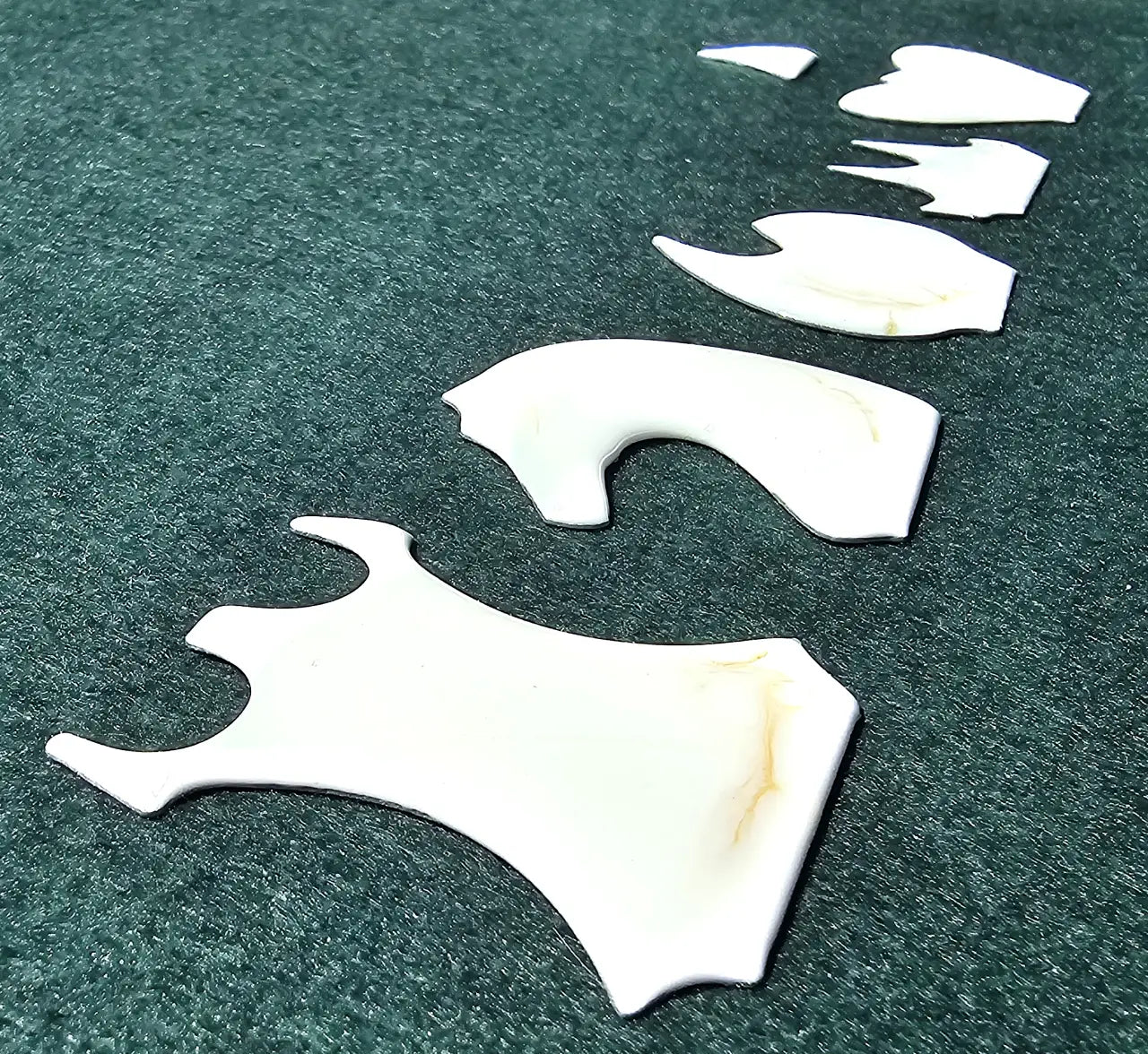 Set of unmounted white and gold resin chess inlays in different piece shapes laid out