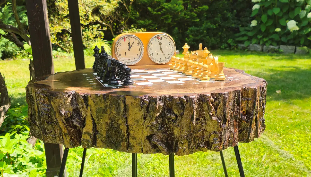 Chess pieces set up for a game on a handmade epoxy chessboard embedded in a natural walnut stump.