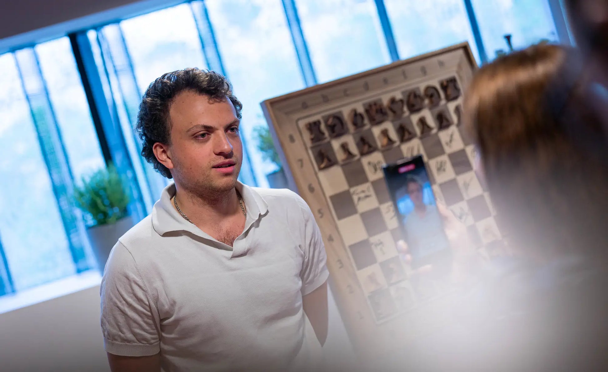 Hans Niemann during Grand Chess Tour Warsaw 2026 with a signed ChessboArt board in the background