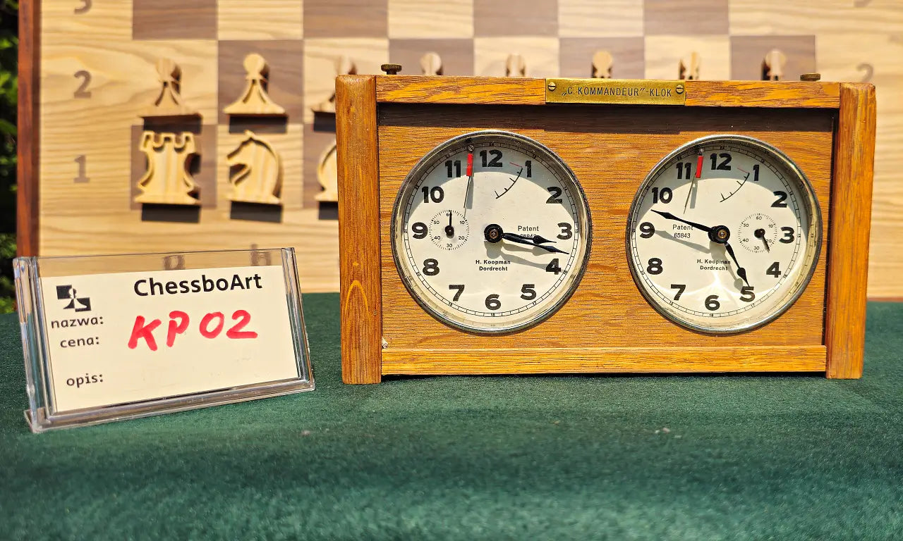 Front view of a working vintage wooden chess clock, model KP02. This 1960s Koopman antique features two analog dials marked 'H. Koopman Dordrecht' and a brass 'C. Kommandeur-Klok' plaque, displayed next to a ChessboArt identification card.