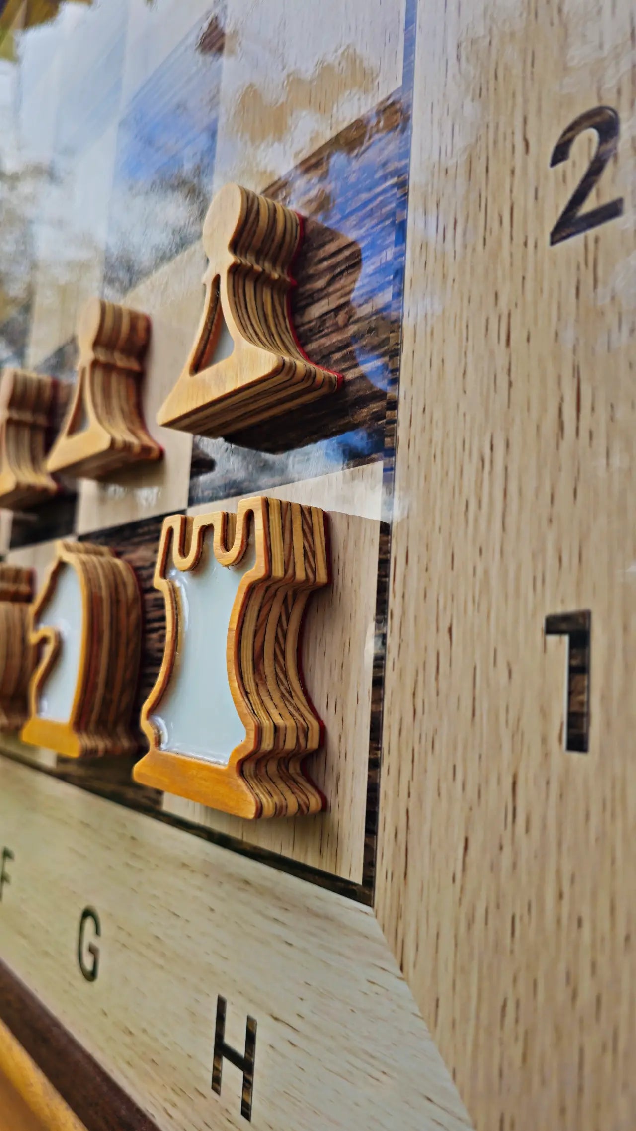 Magnetic plywood chess pieces with resin fills seen from the side on a wall chess board
