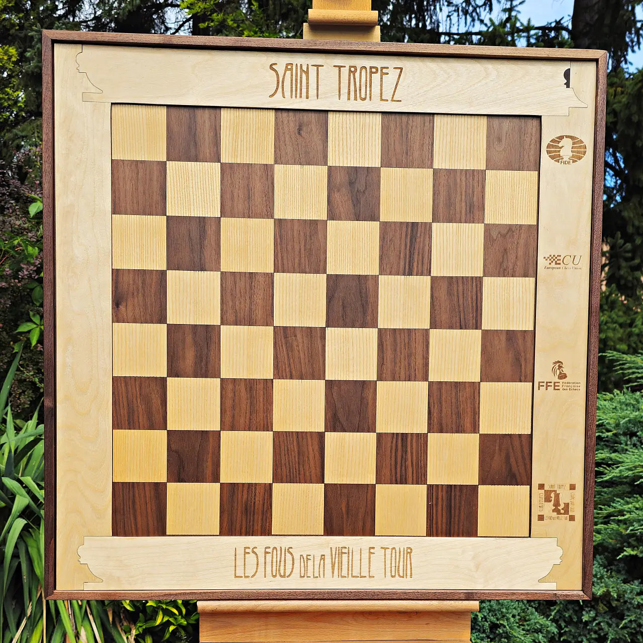 The same wall chess board with the frame flipped to show its birch side engraved with a chess club name and federation logos