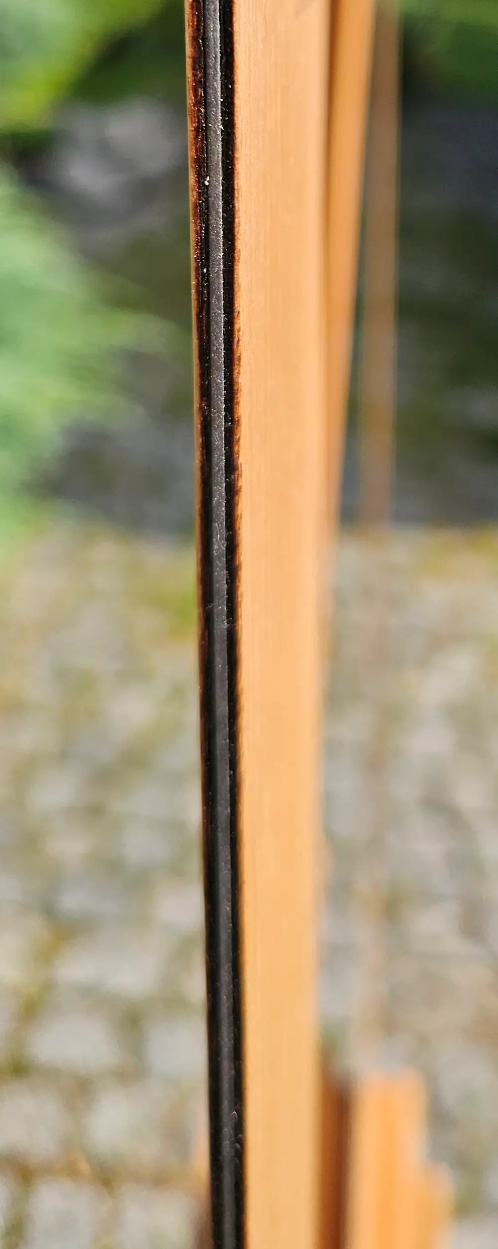 Close-up of the dark steel edge between light wood veneer strips on a personalized wall chess frame