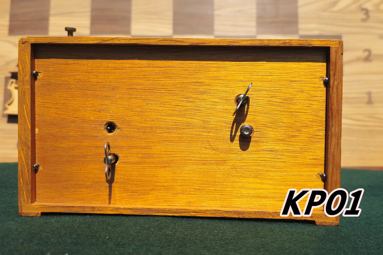 Rear view of a vintage 1960s wooden Koopman chess clock. Shows the warm wood grain of the back panel, secured with screws, and the original metal winding keys and adjustment knobs. Model KP01