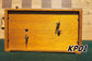 Rear view of a vintage 1960s wooden Koopman chess clock. Shows the warm wood grain of the back panel, secured with screws, and the original metal winding keys and adjustment knobs. Model KP01