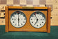Straight-on front view of a vintage 1960s Koopman wooden chess clock. The image clearly shows the two analog dials with 'H. Koopman Dordrecht' text, the brass 'C. Kommandeur-Klok' plaque, and the top push buttons.