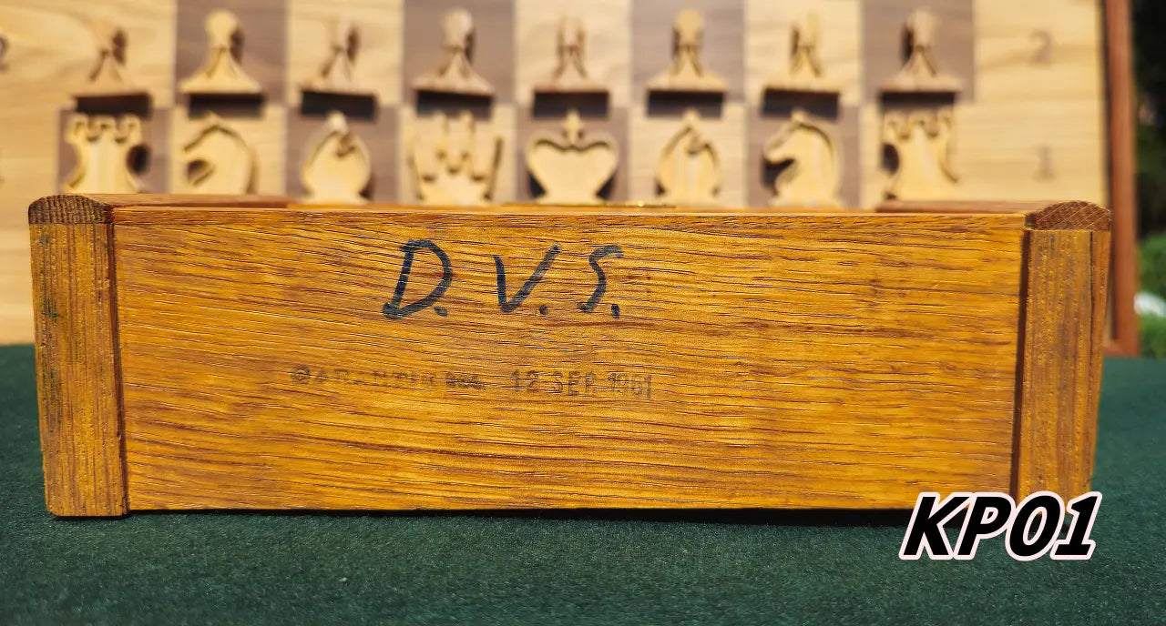 Bottom view of the vintage wooden Koopman chess clock, model KP01. The wooden base features handwritten 'D.V.S.' initials and an authentic, faded production stamp reading '12 SEP 1961', confirming its genuine 1960s origin.