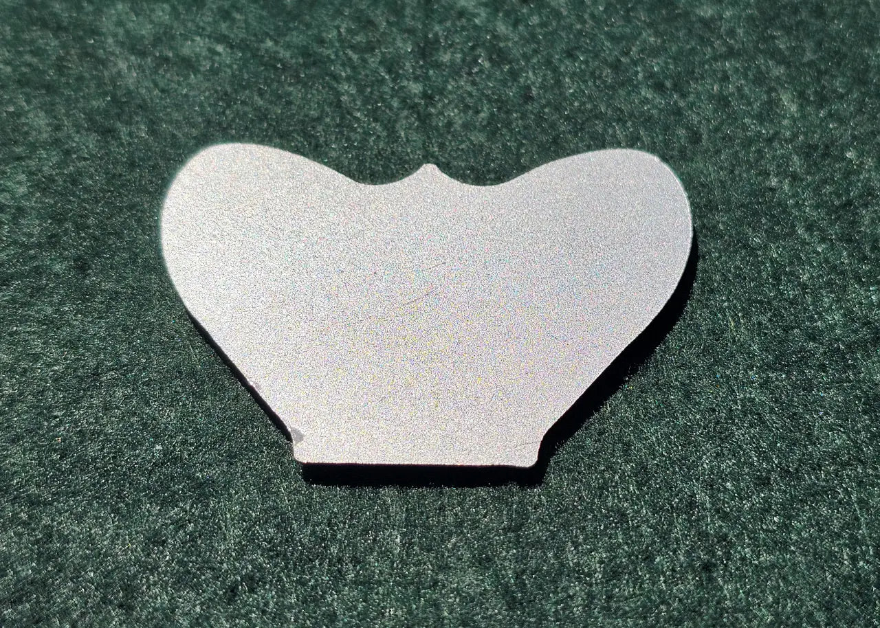 Reverse side of a resin chess inlay showing the metal plate that connects to the piece's magnet