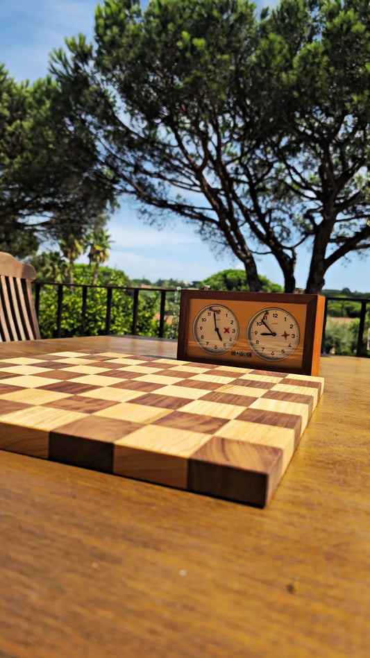 Wooden chessboard and vintage chess clock set on a sunlit hotel terrace table in Saint-Tropez